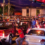 Crowds of people rocking cars celebrating Costa Rica winning world cup
