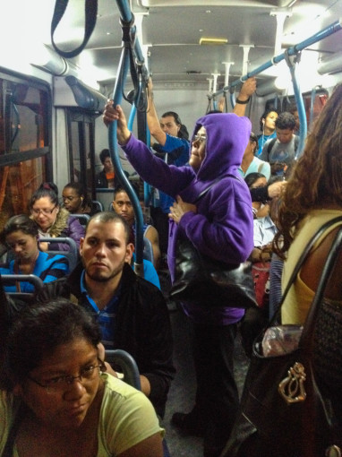 Crowded bus with people standing, giving up their seats for elderly and women